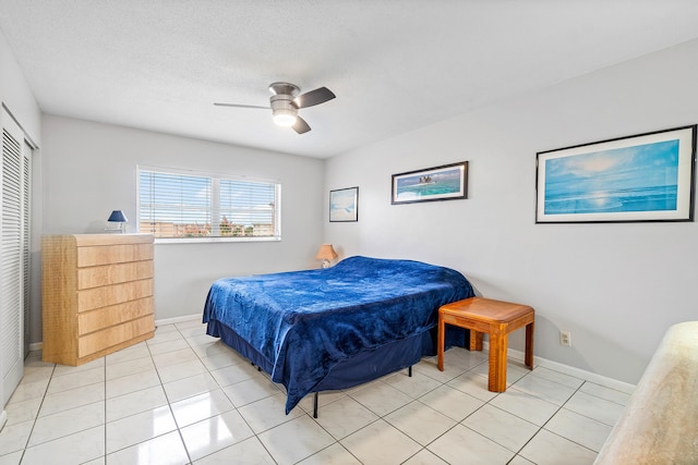 bedroom with ceiling fan, light tile patterned floors, and a textured ceiling