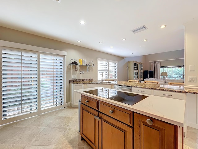 kitchen featuring dishwasher, black electric cooktop, sink, and light stone counters