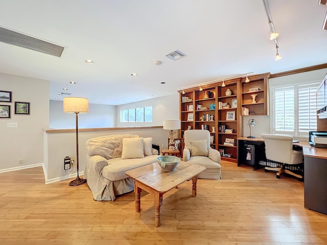 living room featuring rail lighting, plenty of natural light, and light hardwood / wood-style floors