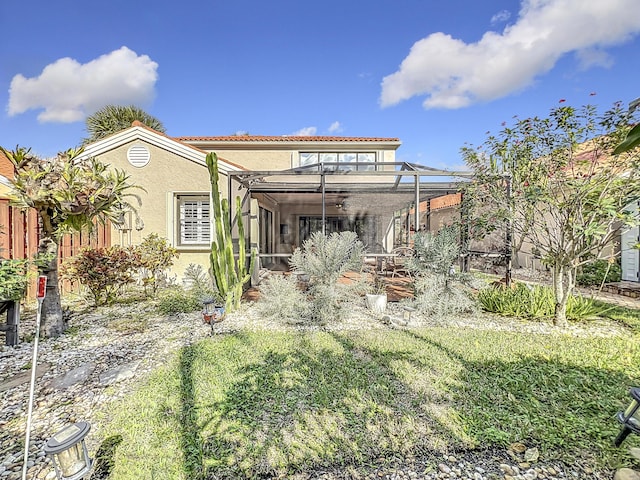 rear view of house with a yard and glass enclosure