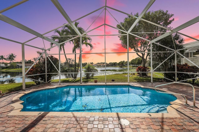 pool at dusk featuring a lanai, a patio, and a water view