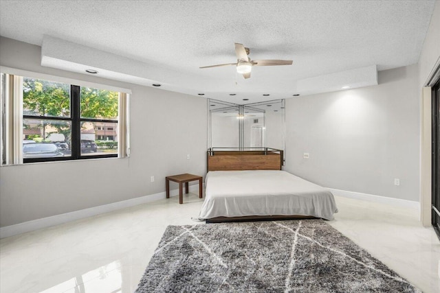 bedroom featuring a textured ceiling, ceiling fan, and a tray ceiling