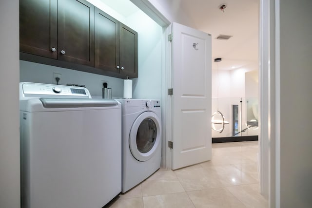 laundry room featuring cabinets, light tile patterned floors, and separate washer and dryer