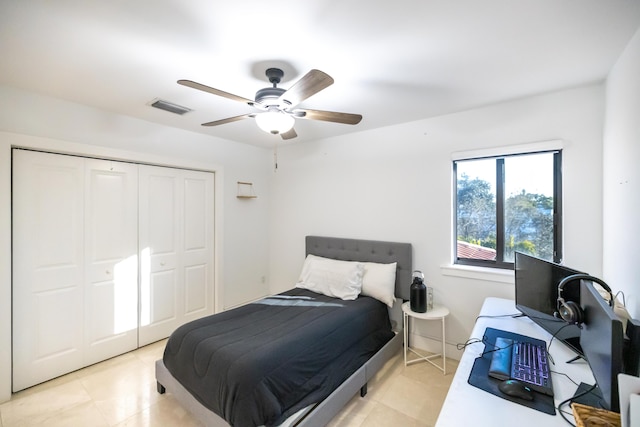 bedroom with ceiling fan, light tile patterned floors, and a closet