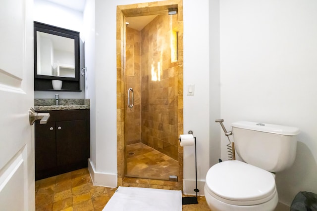 bathroom with toilet, vanity, and a shower with shower door