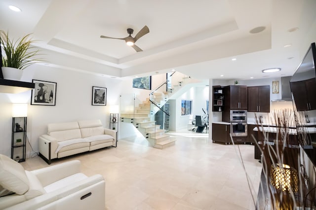 living room with ceiling fan, light tile patterned floors, and a raised ceiling