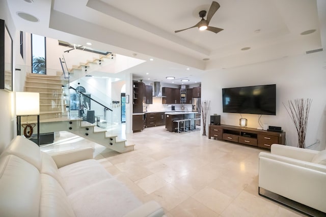 living room featuring a raised ceiling and ceiling fan