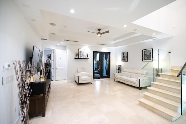 living room featuring a raised ceiling and ceiling fan