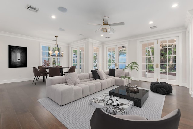 living room featuring dark hardwood / wood-style floors, crown molding, ceiling fan with notable chandelier, and french doors