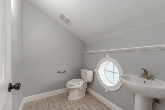 bathroom featuring toilet, lofted ceiling, and sink