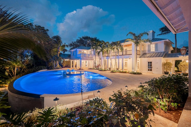 view of pool featuring a hot tub, pool water feature, and a patio