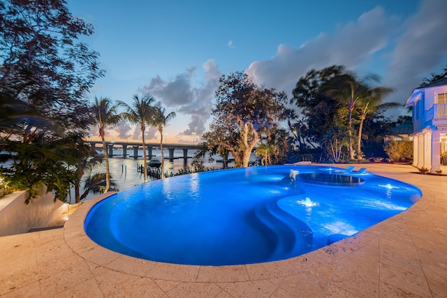 pool at dusk featuring a water view