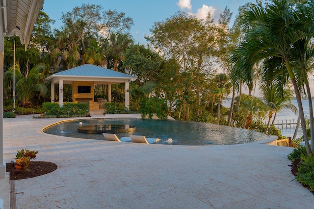 view of pool featuring a patio area, an outdoor fireplace, and a gazebo