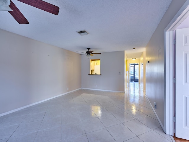 tiled empty room with ceiling fan and a textured ceiling