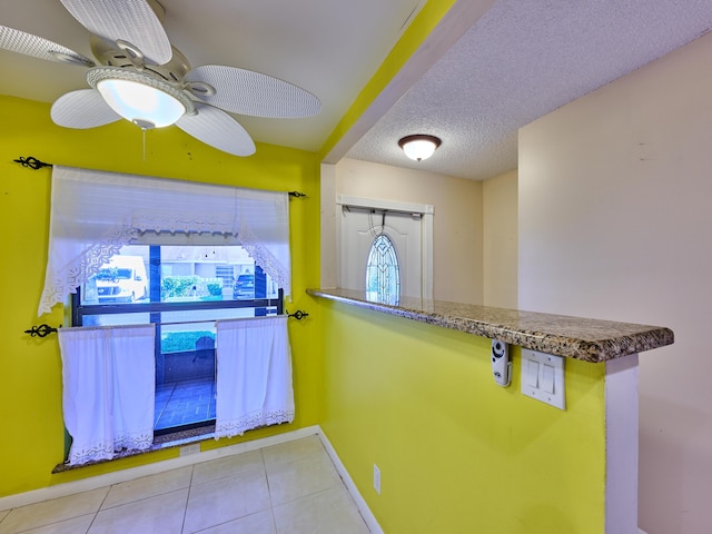 interior space with ceiling fan, plenty of natural light, a textured ceiling, and light tile patterned floors