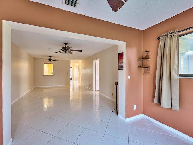 empty room featuring light tile patterned floors, a textured ceiling, and ceiling fan