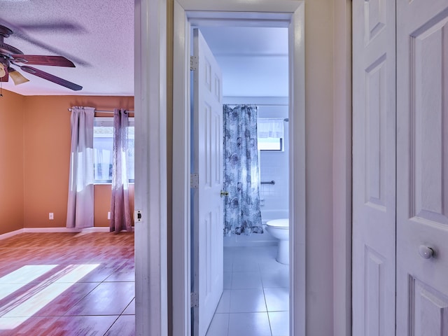 hallway with light tile patterned floors, a wealth of natural light, and a textured ceiling