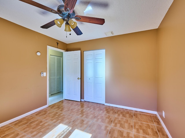 unfurnished bedroom with ceiling fan, a textured ceiling, and light tile patterned floors