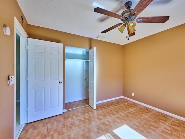 unfurnished bedroom with ceiling fan, tile patterned flooring, a closet, and a textured ceiling