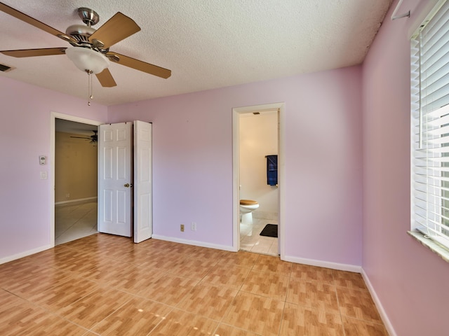 unfurnished bedroom with ceiling fan, connected bathroom, multiple windows, and light tile patterned floors