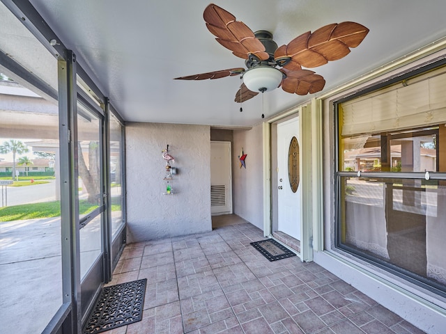 unfurnished sunroom with ceiling fan