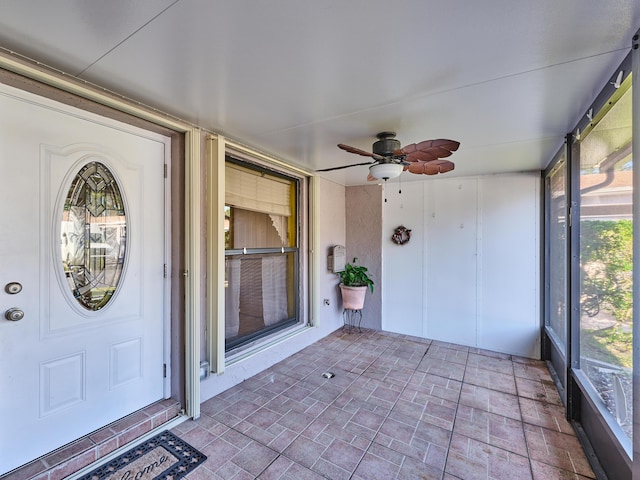 unfurnished sunroom with ceiling fan