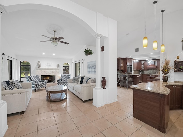 tiled living room with ceiling fan, vaulted ceiling, and ornate columns