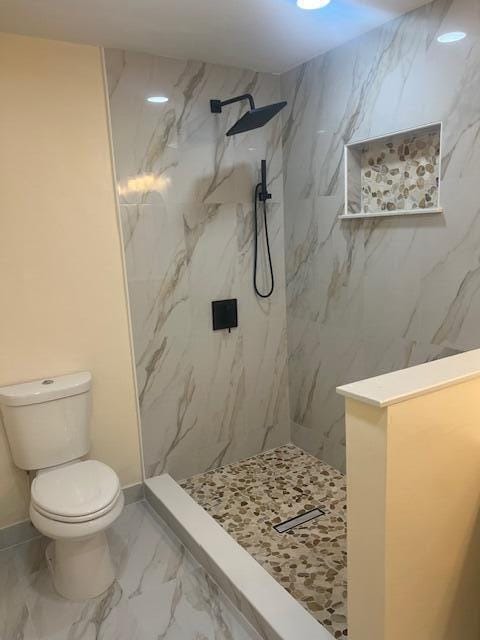 bathroom with toilet and a tile shower