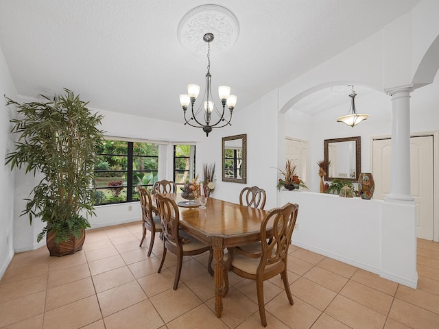 dining space featuring ornate columns, lofted ceiling, light tile patterned floors, and a notable chandelier