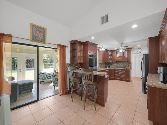 kitchen featuring light tile patterned floors, a kitchen bar, kitchen peninsula, and appliances with stainless steel finishes