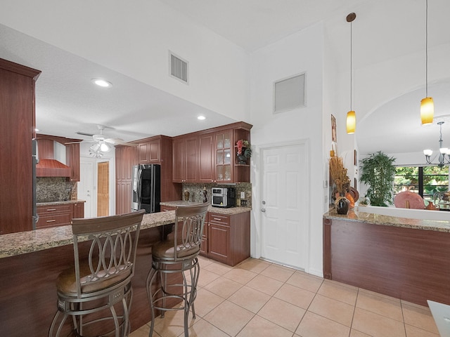 kitchen with light stone countertops, a breakfast bar area, pendant lighting, and stainless steel fridge with ice dispenser