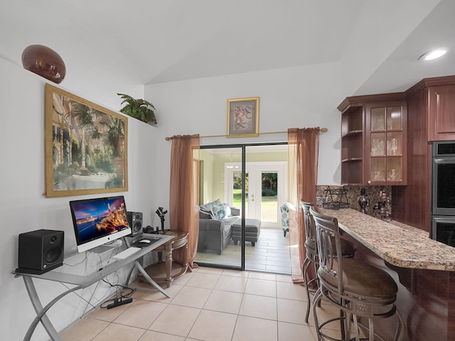 kitchen featuring french doors, light tile patterned flooring, light stone counters, tasteful backsplash, and double oven