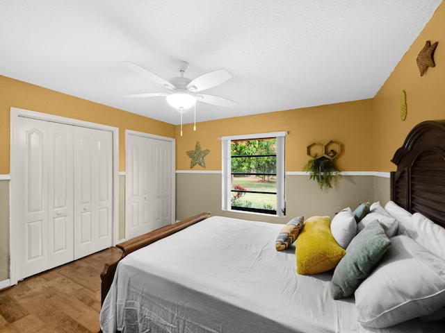 bedroom featuring multiple closets, ceiling fan, and wood-type flooring