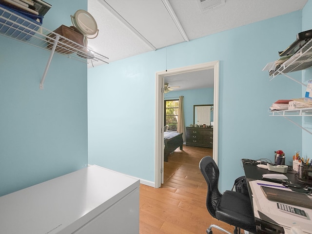 home office with light hardwood / wood-style flooring and a textured ceiling