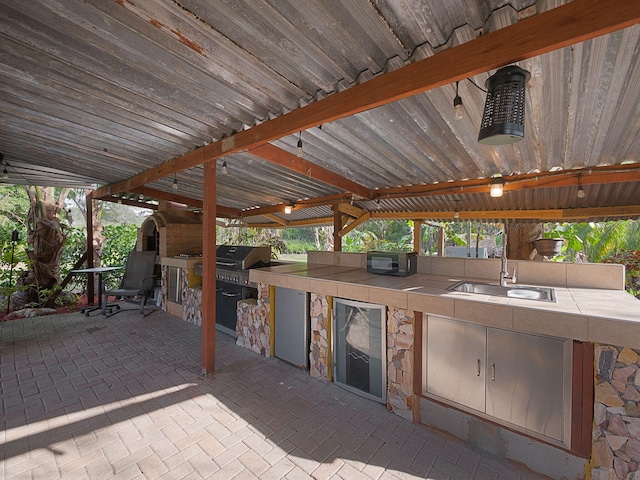 view of patio / terrace with a grill, an outdoor kitchen, sink, and beverage cooler