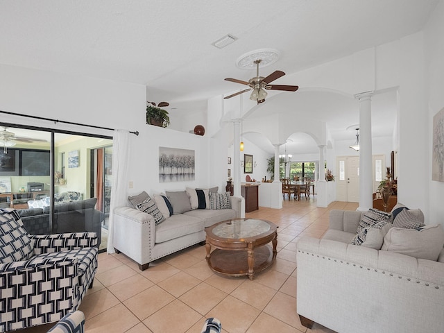 tiled living room with lofted ceiling, decorative columns, and ceiling fan