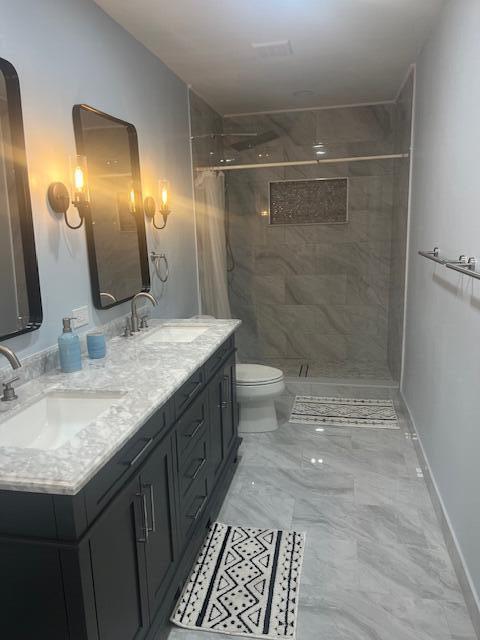 bathroom featuring toilet, vanity, and a tile shower