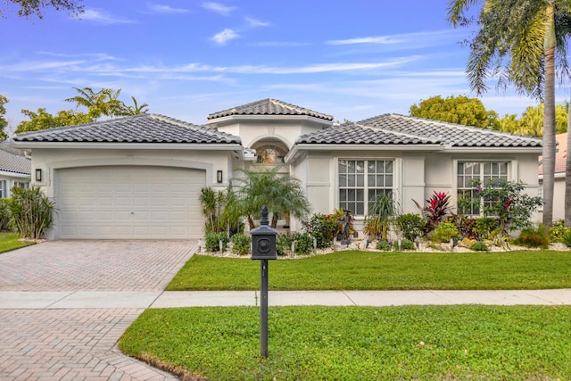 mediterranean / spanish-style home featuring a front lawn and a garage