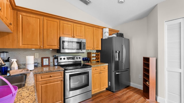 7961 Mansfield Hollow Rd, Delray Beach, FL 33446 - kitchen featuring appliances with stainless steel finishes, lofted ceiling, tasteful backsplash, dark wood-style floors, and light stone countertops
