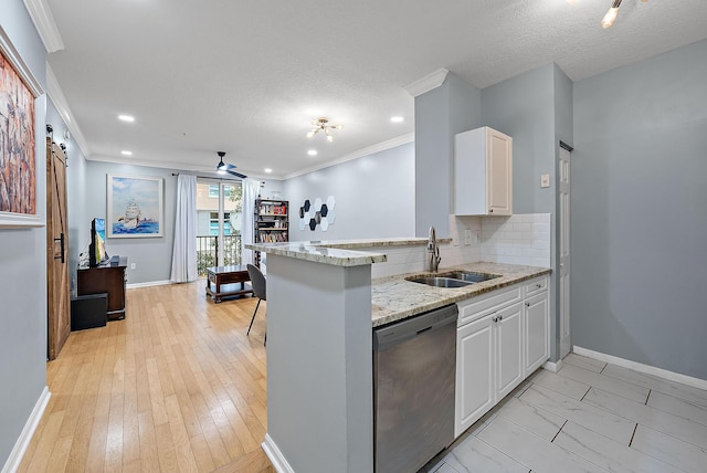 kitchen with white cabinets, dishwasher, sink, kitchen peninsula, and a barn door