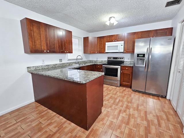 kitchen with kitchen peninsula, stainless steel appliances, dark stone countertops, light hardwood / wood-style flooring, and sink