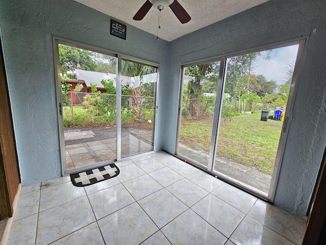 unfurnished sunroom featuring ceiling fan and a wealth of natural light