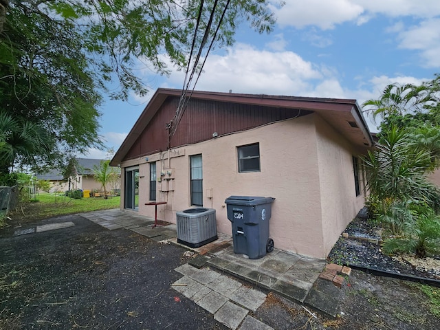 back of property with central air condition unit and a patio