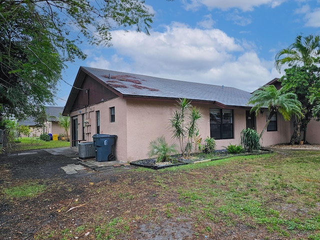 rear view of house featuring a lawn and central AC