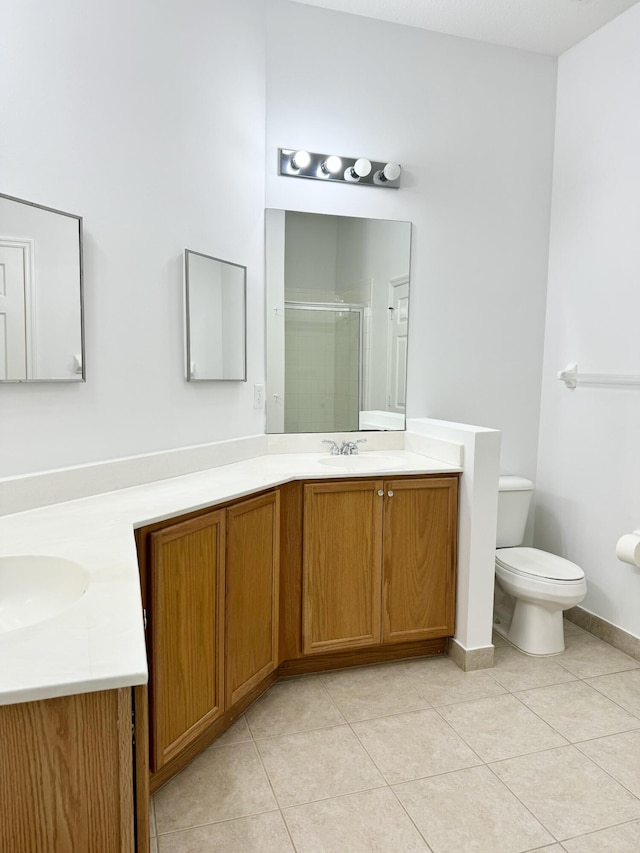 bathroom featuring a shower with shower door, vanity, tile patterned floors, and toilet