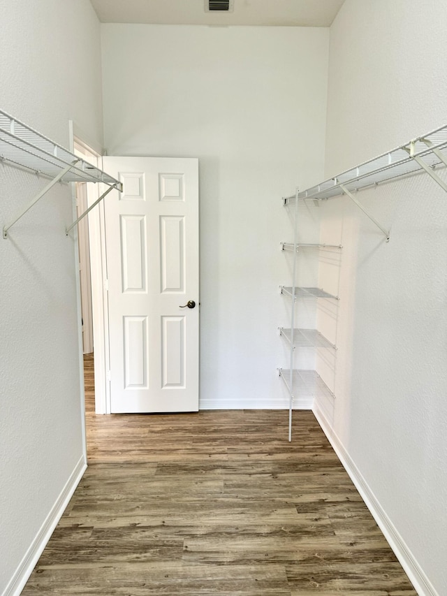 walk in closet with dark hardwood / wood-style flooring