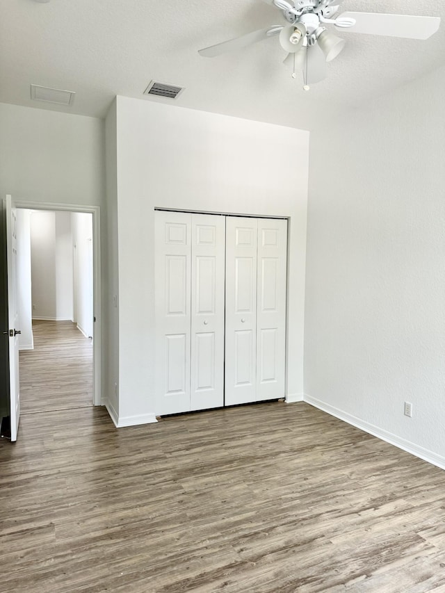 unfurnished bedroom with ceiling fan, a closet, and light wood-type flooring