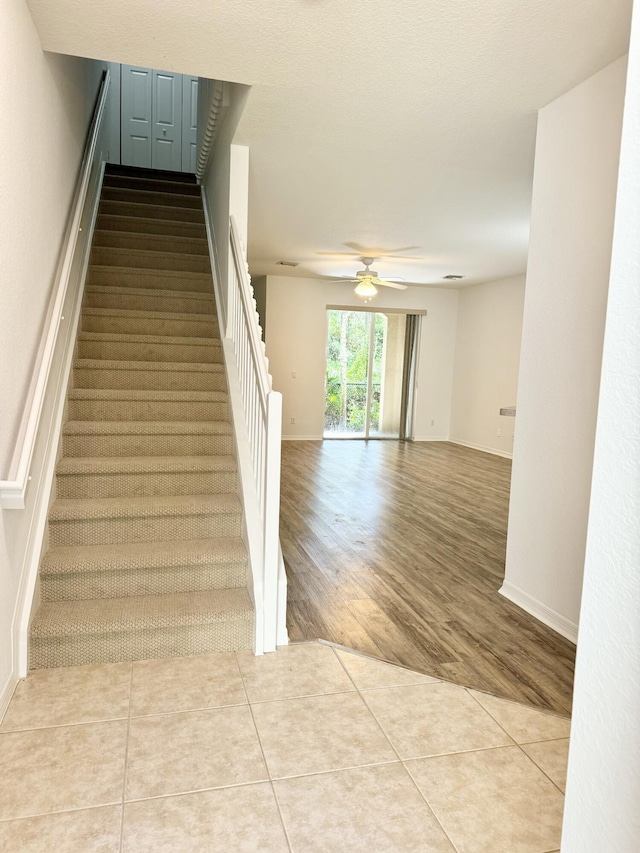 stairs featuring ceiling fan and tile patterned flooring