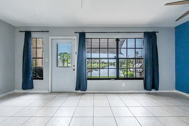 tiled spare room with ceiling fan and a water view