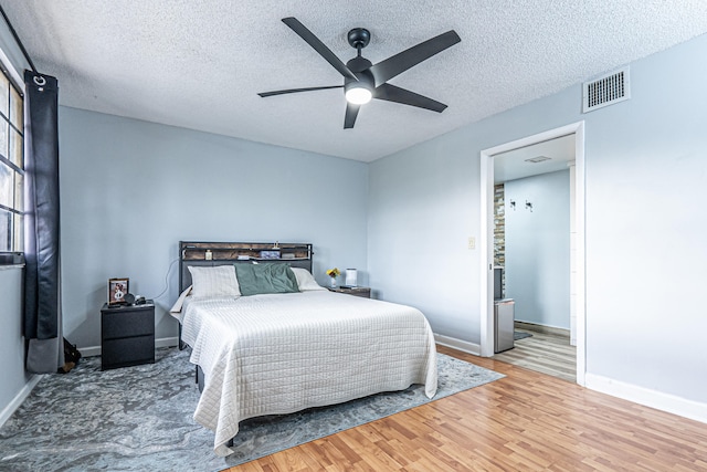 bedroom with ceiling fan, wood-type flooring, and a textured ceiling